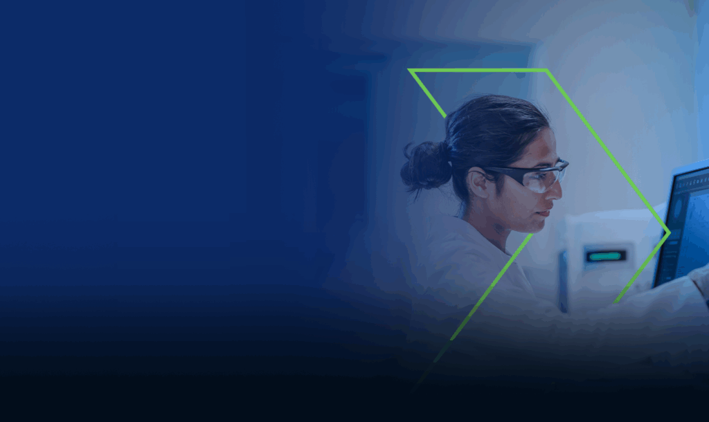 A woman scientist researcher is working on a computer in a lab setting.
