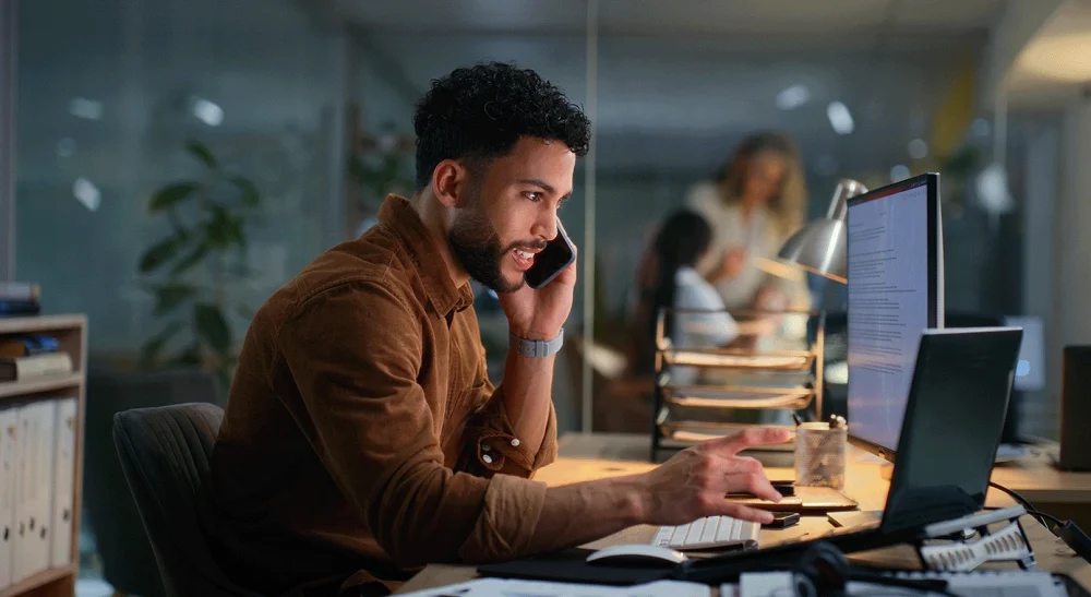 Man on the phone in an office setting helping a client, representing our team is ready to collaborate at SAI MedPartners.
